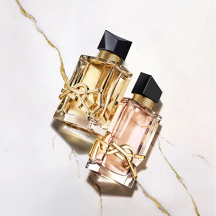 YSL Libre perfume bottle: clear rectangular glass, gold-toned YSL logo, black asymmetrical cap, gold-toned neck band. One has