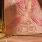 Gold-toned compact with an embossed orchid design in shimmery pink and peach powder, accented with white glitter.