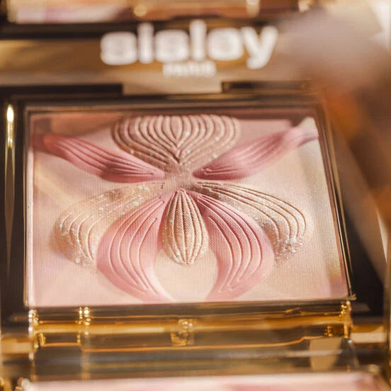 Gold-toned compact with a light pink shimmery powder embossed with a pink and light gold-toned orchid flower design.