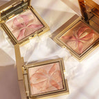 Gold-toned square compact with shimmery pink pressed powder featuring an embossed rose orchid design with textured, gold-tone