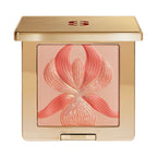 Square gold-toned compact with a red SS logo. Contains shimmery peach-bronze powder with an embossed coral orchid design.