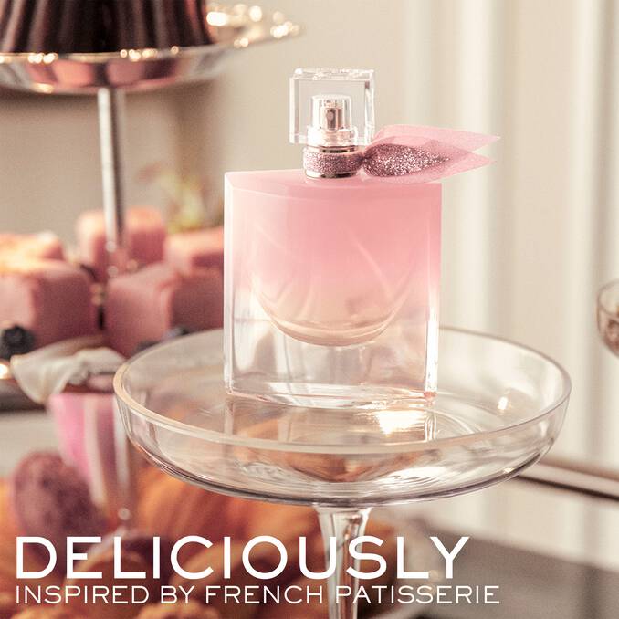 Clear glass perfume bottle with light pink liquid, gold-toned sprayer, and a glittery pink sheer fabric bow.