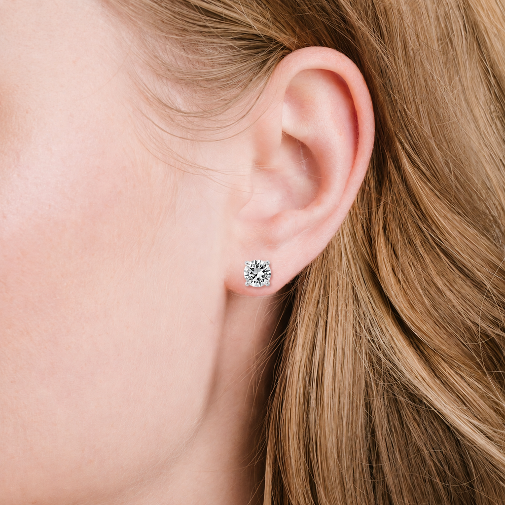 A single stud earring with a round, clear, faceted stone in a four-prong, silver-toned setting.