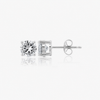 Pair of silver-toned stud earrings, each with a round, brilliant-cut clear stone in a 4-prong setting. One shows its post and