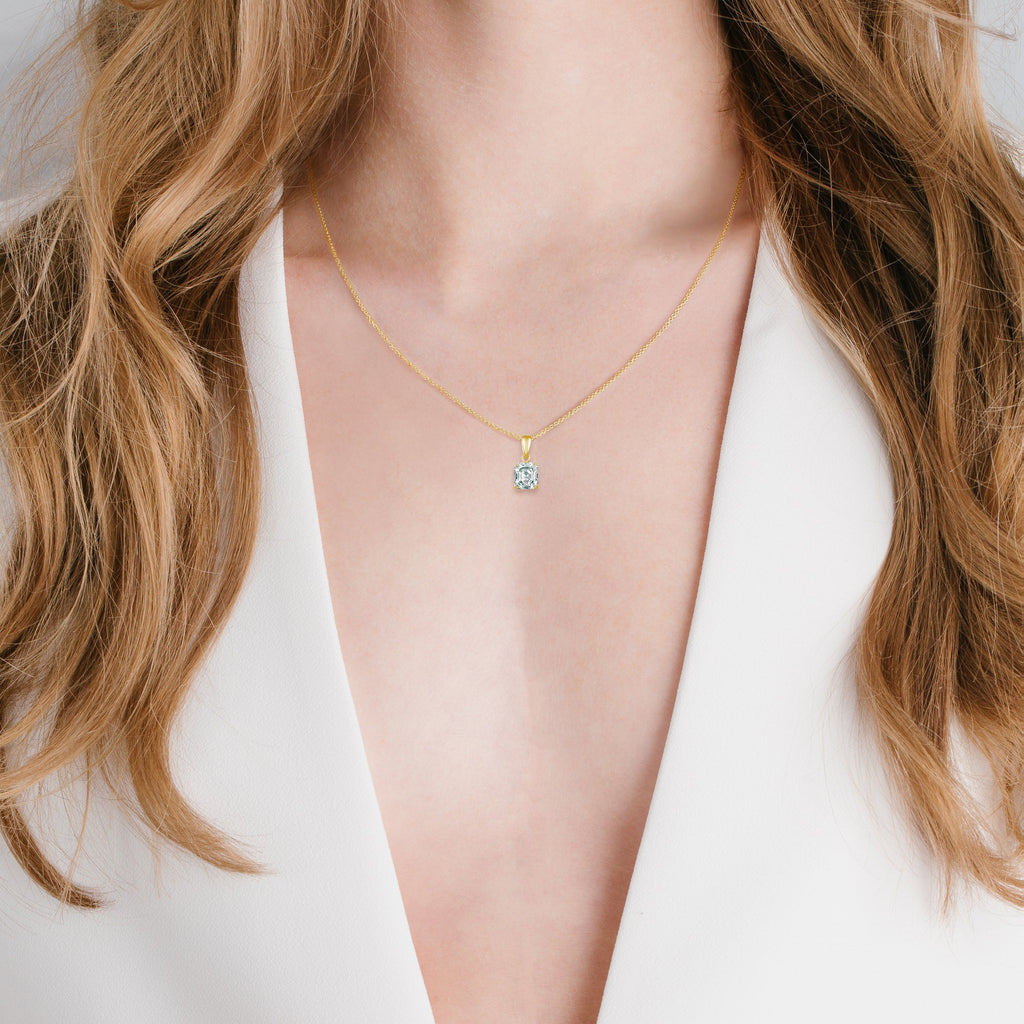 Gold-toned chain necklace with a square, clear stone pendant in a four-prong gold-toned setting.