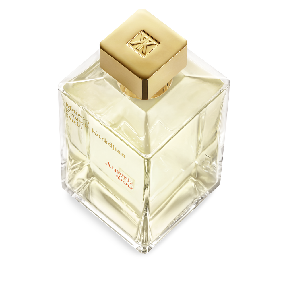 Clear square glass perfume bottle with light yellow liquid, a gold-toned square cap with an embossed logo, and black and red