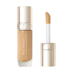 Light beige liquid concealer in a clear glass bottle with a gold-toned cap and a separate applicator wand with a flocked tip.