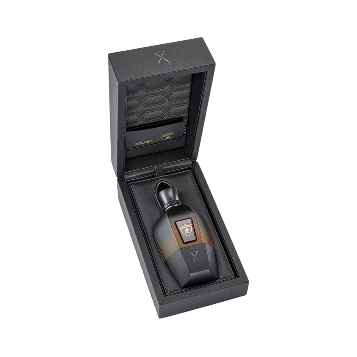 Black hinged box open to reveal a perfume bottle. The bottle is dark brown to amber ombre with a black cap, gold-toned emblem