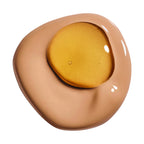 A swatch of light brown foundation with a golden, shimmery liquid layered on top, showing reflections.