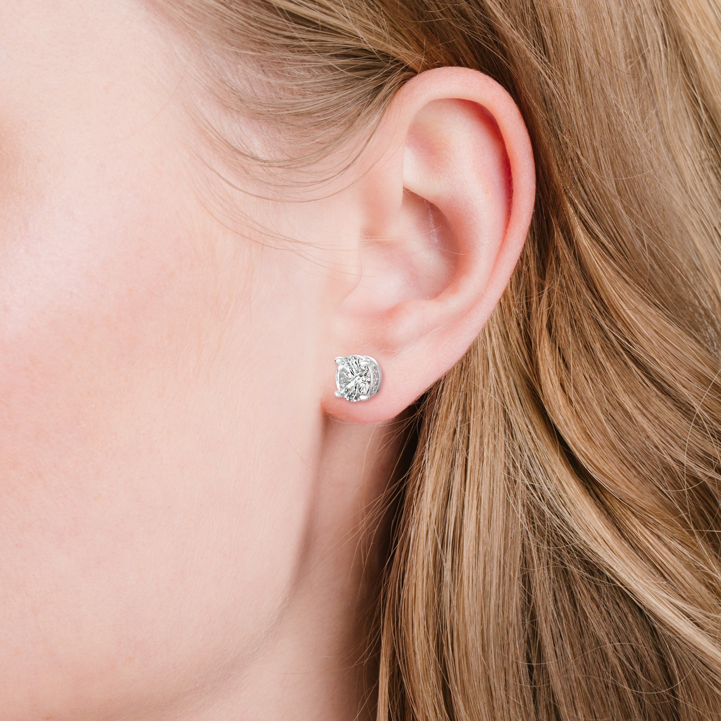 A round stud earring with a clear faceted stone surrounded by smaller pave stones in a silver-toned setting.