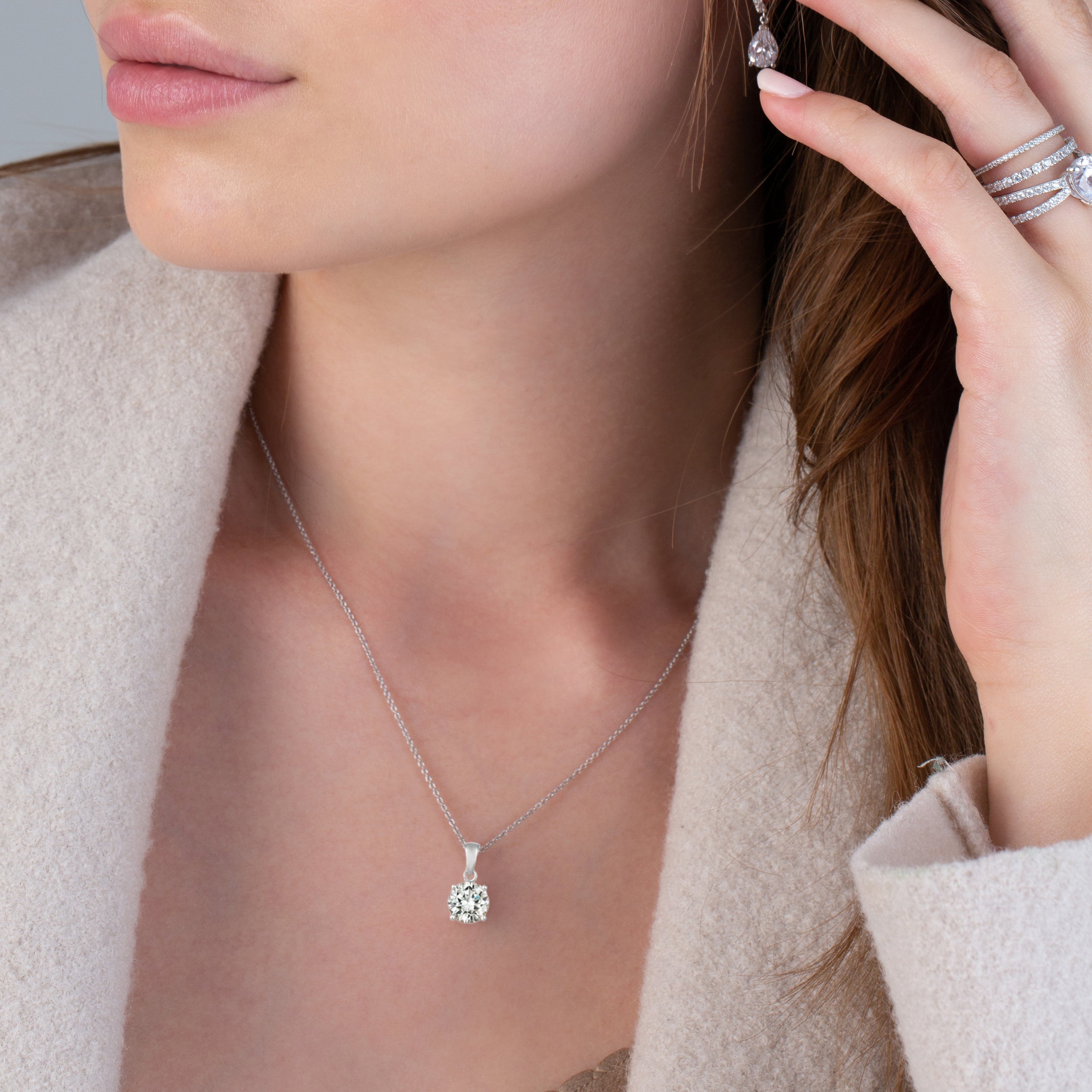 Silver-toned chain necklace with a round clear stone pendant in a four-prong setting.