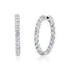 Pair of large round hoop earrings in silver-toned metal, each adorned with clear brilliant-cut stones.