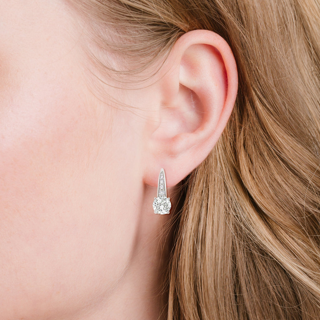 Silver-toned leverback earring with a large round clear stone and smaller clear stones set along the tapered top.