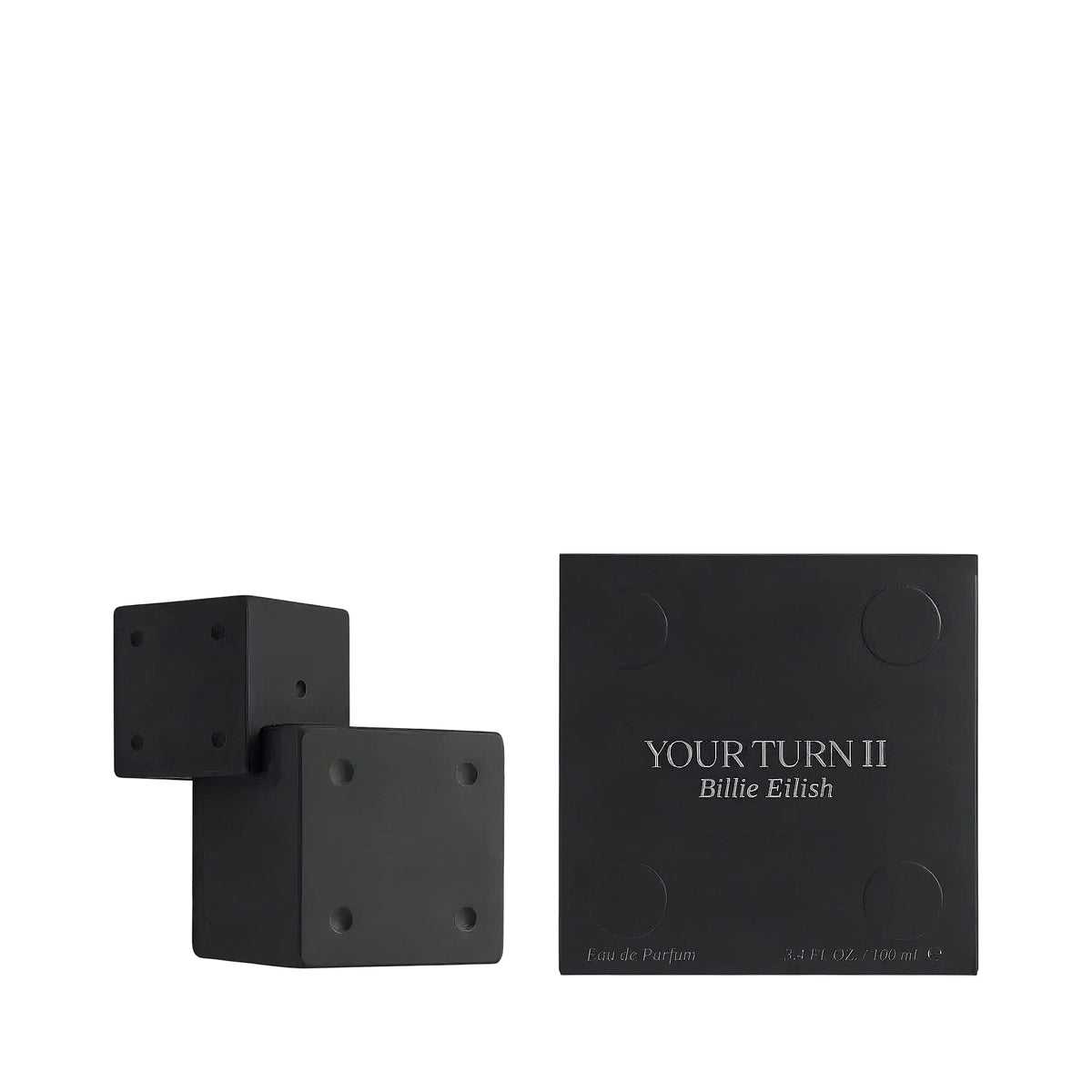 Black perfume bottle, two connected cubes with round indents, beside a black box with "YOUR TURN II Billie Eilish" and matchi