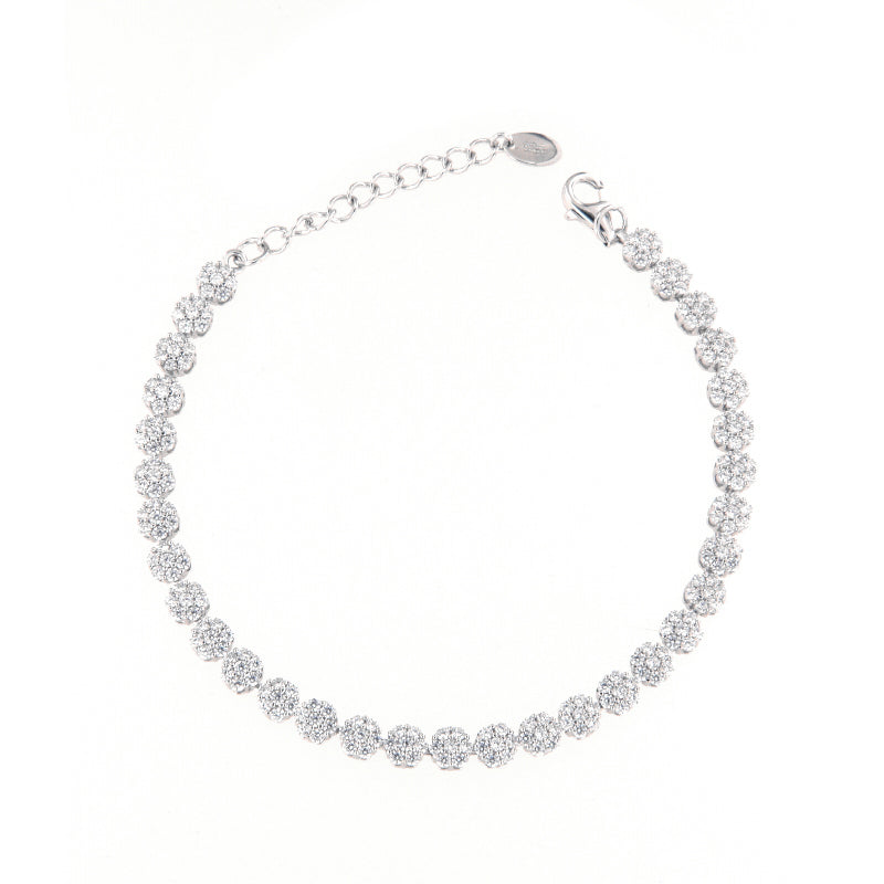 Silver-toned bracelet featuring a continuous line of circular clusters, each adorned with clear faceted stones, a lobster cla