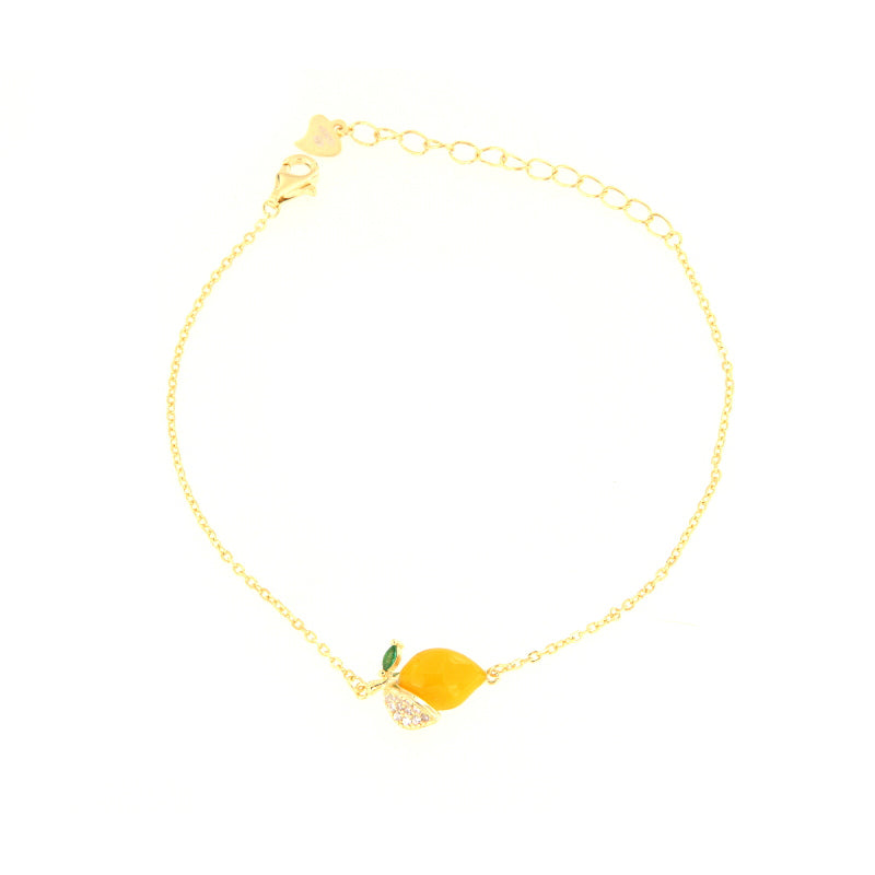 Gold-toned chain bracelet with a bright yellow lemon-shaped charm, featuring a green leaf and a segment embellished with clea