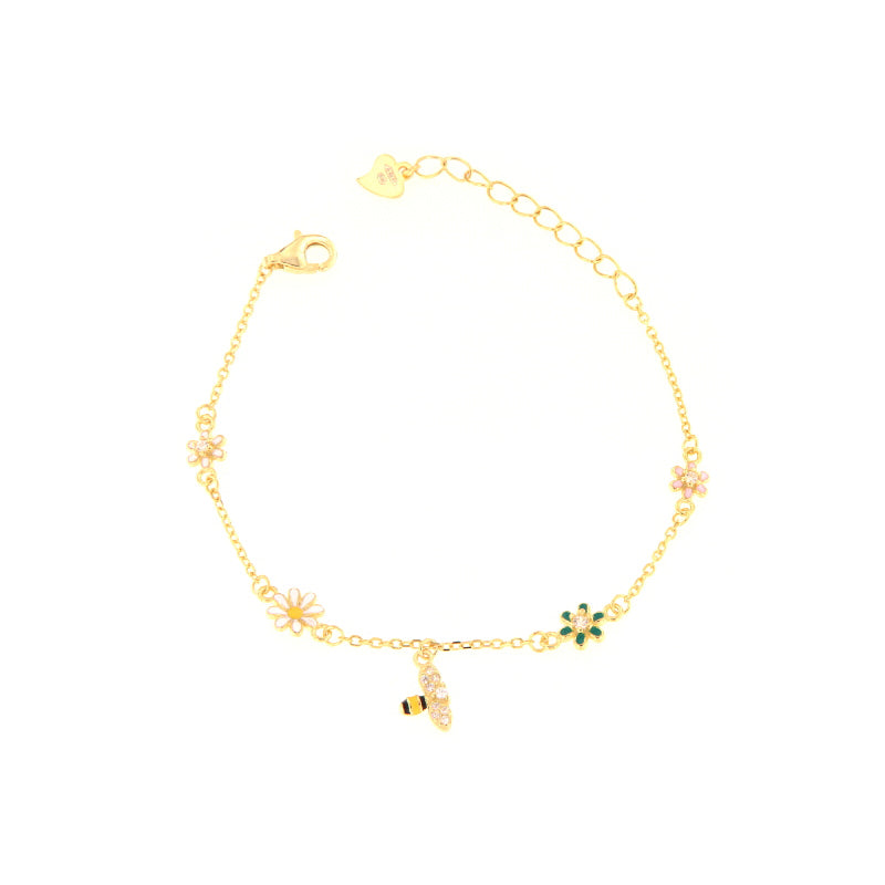 Gold-toned chain bracelet with a bee charm and multiple flower charms in pink, green, and white with clear stones.