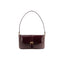 Front view of the BY FAR Miranda baguette bag featuring a purple grape-colored woven raffia body, a smooth dark leather front flap, and a gold buckle against a grey background.