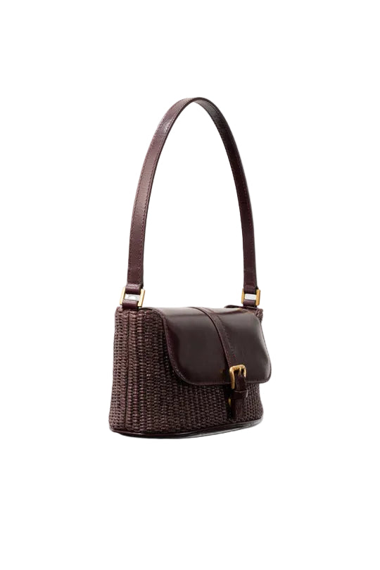 Side view of the BY FAR Miranda baguette bag featuring a purple grape-colored woven raffia body, a smooth dark leather front flap, and a gold buckle against a grey background.