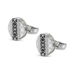 Pair of silver-toned cufflinks. Each round face features a black geometric pattern, 'S' monograms, and a creamy mother-of-pea