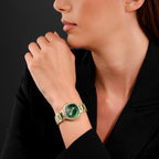 Gold-toned watch with a round case, crystal-encrusted bezel, green iridescent dial, and a link bracelet.