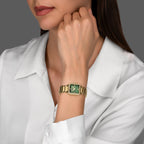 Gold-toned watch with a rectangular green MOP dial, bezel encrusted with clear stones, and a gold-toned link bracelet.