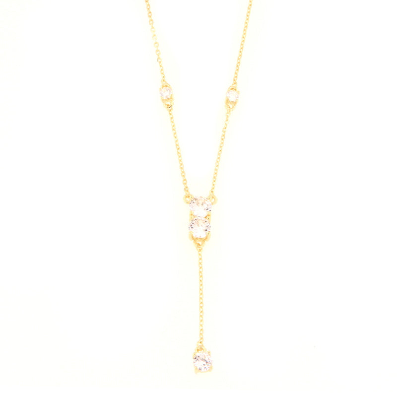Gold-toned lariat necklace with a fine chain and five clear, brilliant-cut stones, including a central drop design.