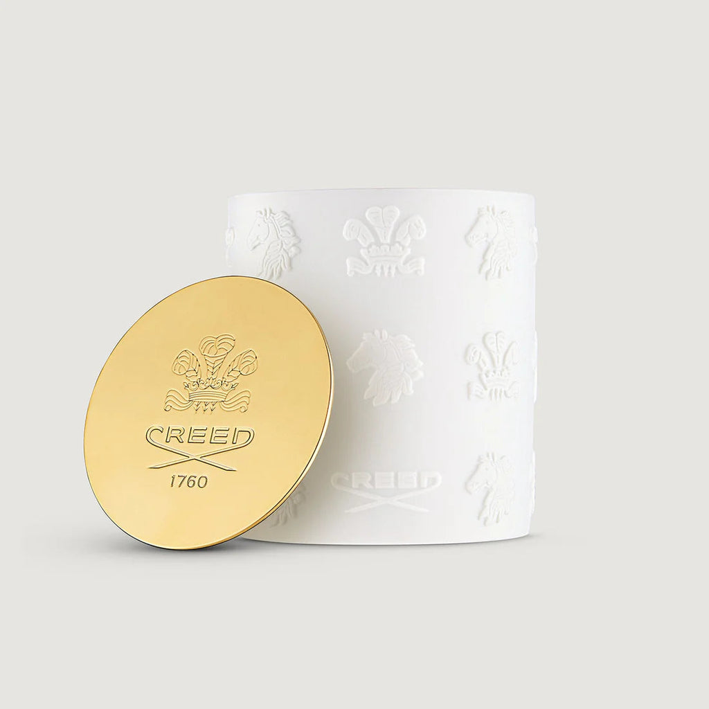 White cylindrical candle with embossed horse and crown patterns. Gold-toned lid with 'CREED 1760' and crest.