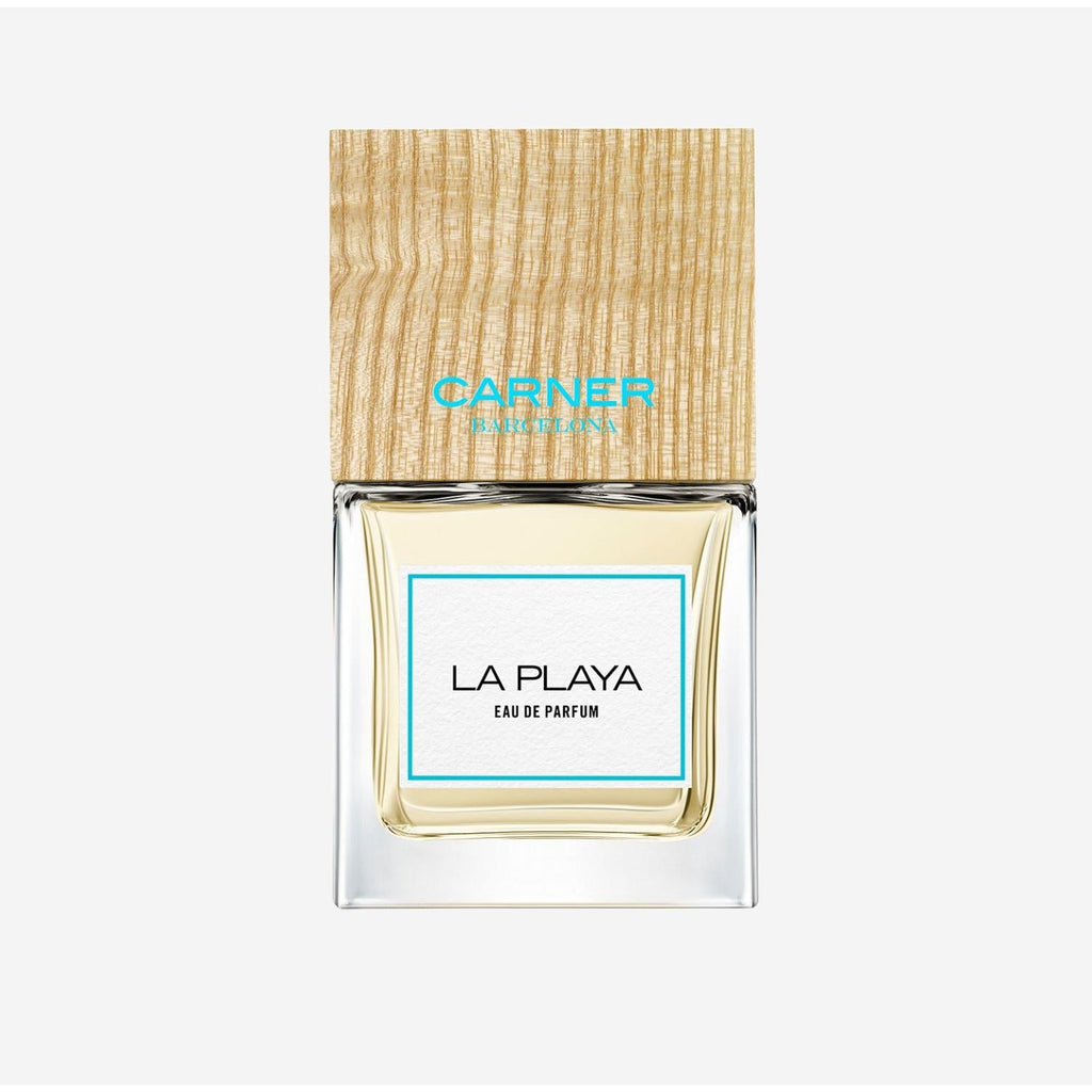 Carner Barcelona La Playa 100ml perfume bottle with a distinctive square wooden cap, presented next to its minimalist white retail box featuring clean black typography.
