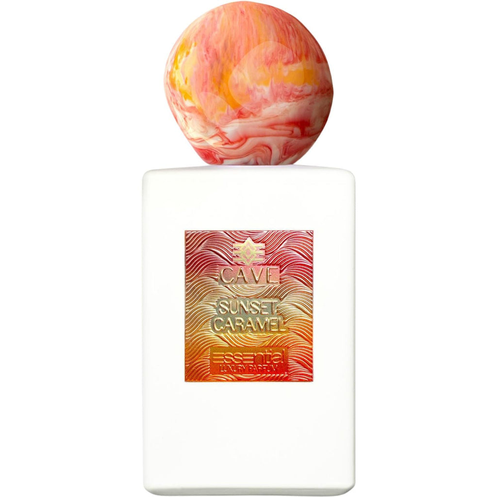 A bottle of Cave Sunset Caramel Essential Luxury Parfum featuring a matte white rectangular body and a unique spherical cap with a red, orange, and white marble swirl pattern. The front displays a textured metallic label with a wavy pattern and a sunset-inspired orange-to-gold gradient.
