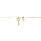 Gold-toned chain bracelet with a key charm featuring a crystal-encrusted 'CC' bow and a white pearl charm.