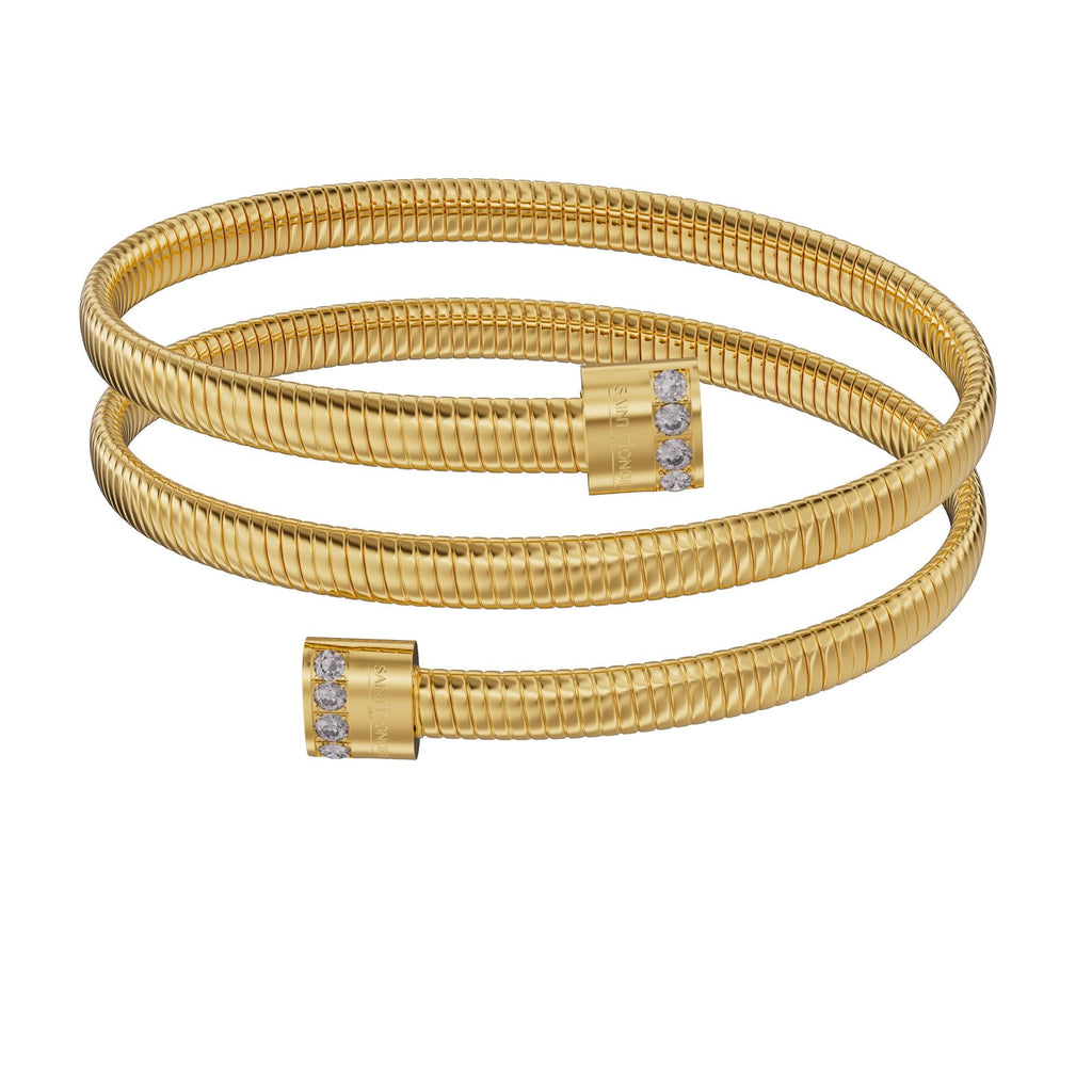 A frontal studio perspective shot of the Saint Honoré Tubogas multi-layered gold-plated wrap bangle against a white background, highlighting the engraved logo end caps set with rows of clear crystals.