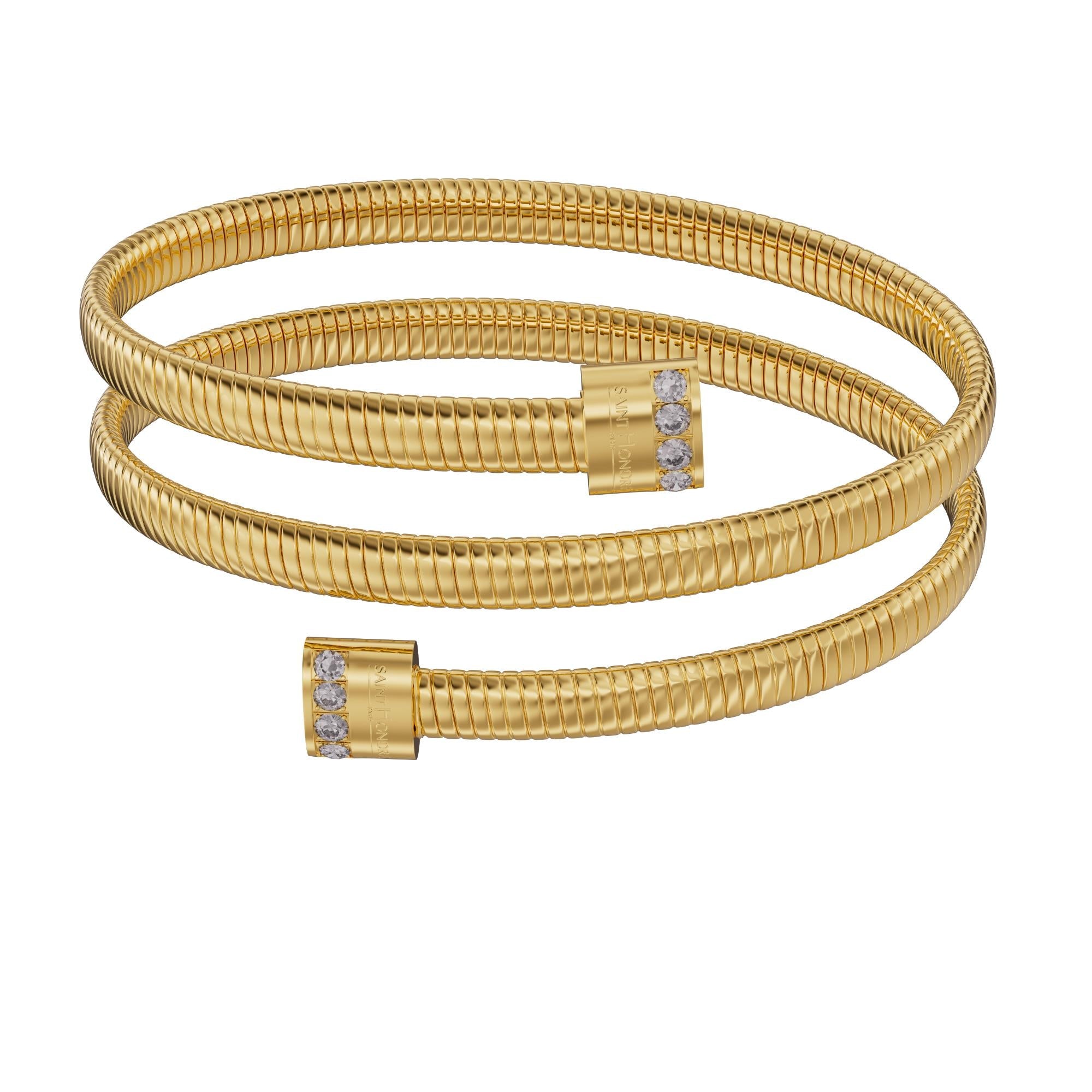 A frontal studio perspective shot of the Saint Honoré Tubogas multi-layered gold-plated wrap bangle against a white background, highlighting the engraved logo end caps set with rows of clear crystals.
