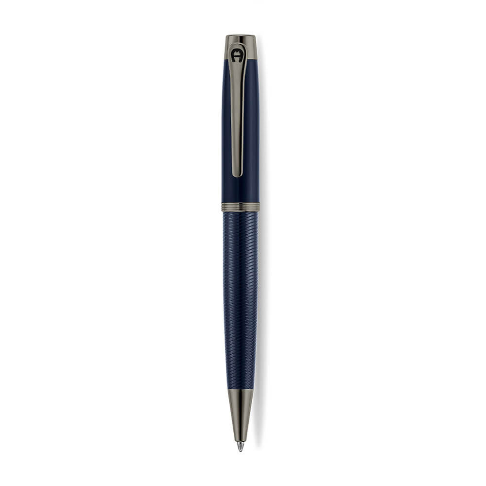 A high-resolution studio presentation of the Aigner Albano men's luxury ballpoint pen displayed horizontally against a white background, highlighting its metal barrel finished with a textured, spiral-grooved blue lower grip, a smooth blue upper body, a multi-ringed gunmetal center band, an IP gunmetal pocket clip featuring the horseshoe logo, and the matching gunmetal writing tip cone.