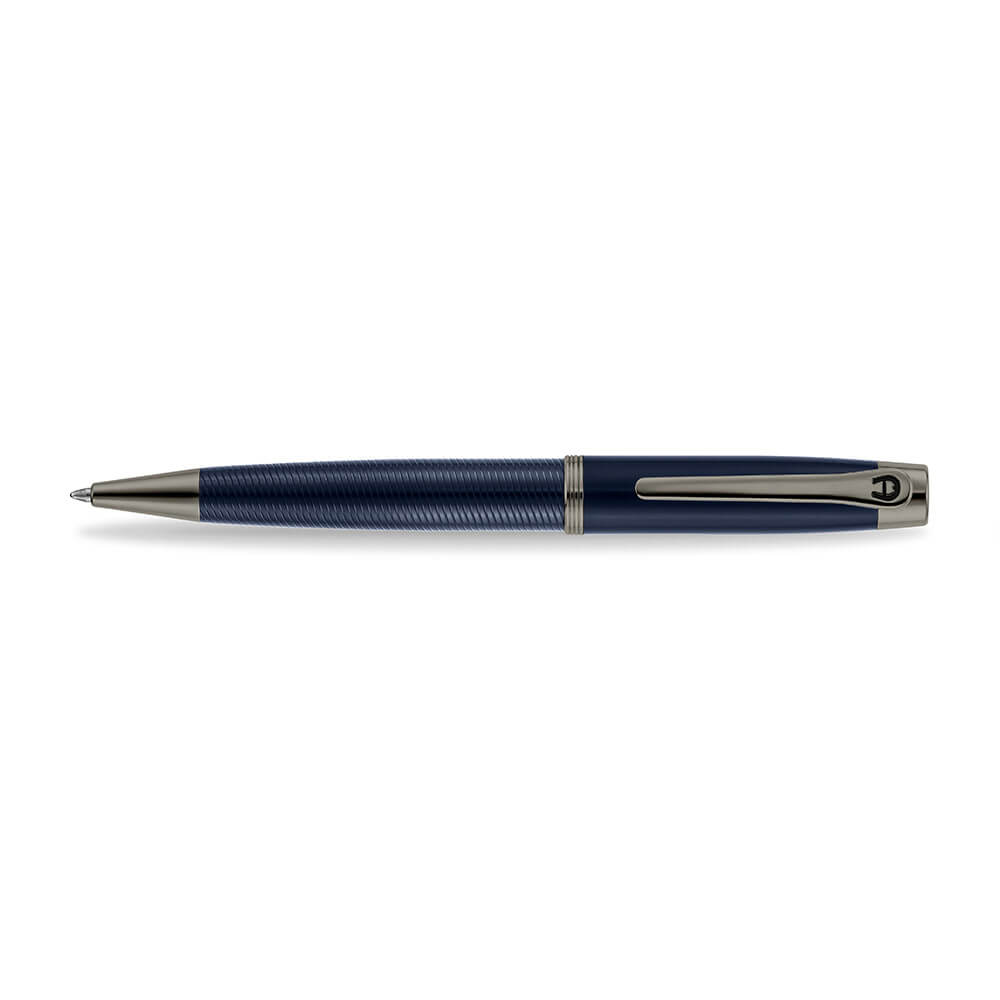 A high-resolution studio presentation of the Aigner Albano men's luxury ballpoint pen displayed horizontally against a white background, highlighting its metal barrel finished with a textured, spiral-grooved blue lower grip, a smooth blue upper body, a multi-ringed gunmetal center band, an IP gunmetal pocket clip featuring the horseshoe logo, and the matching gunmetal writing tip cone.