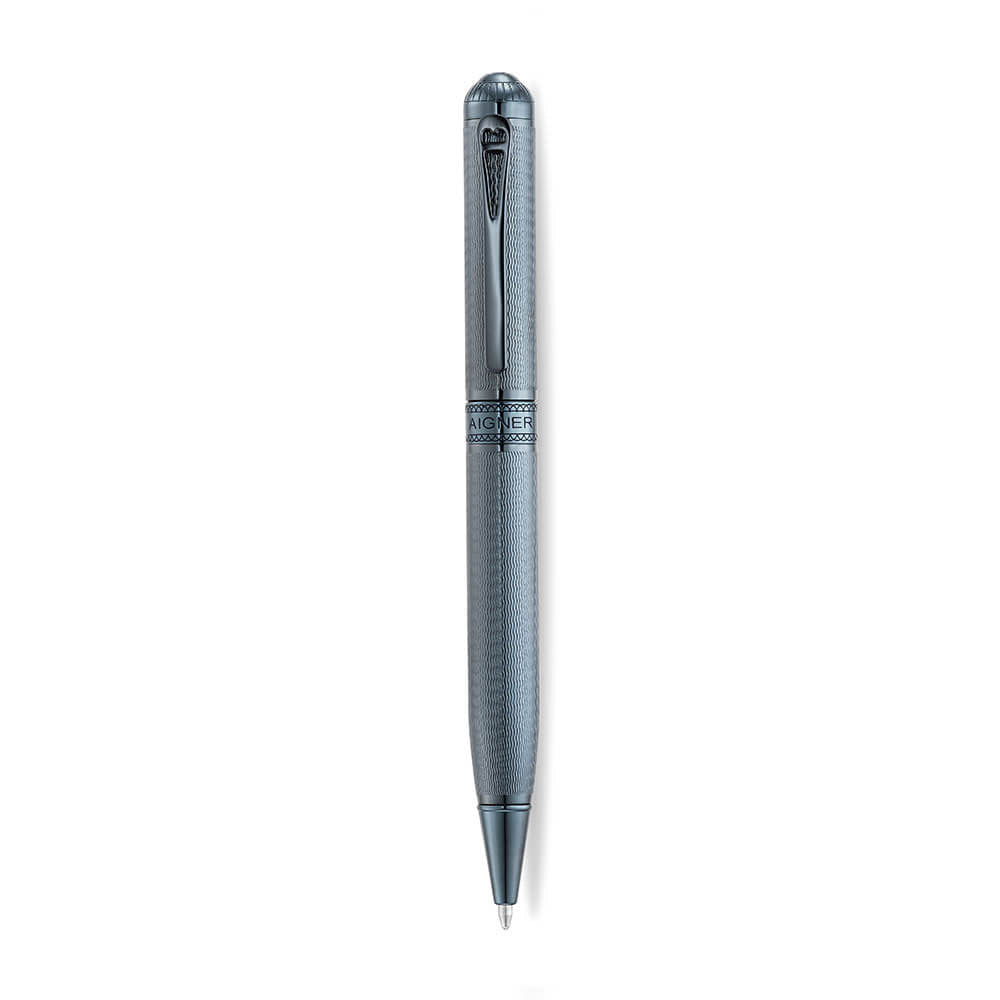 A high-resolution studio shot of the Aigner Ettoro men's luxury ballpoint pen displayed horizontally, highlighting its textured gunmetal-blue and chrome brass barrel, the central engraved Aigner brand band, the integrated pocket clip, and the exposed fine writing tip.