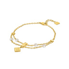 Gold-toned double-strand bracelet with white pearls, a rectangular bar charm, and a square logo charm.