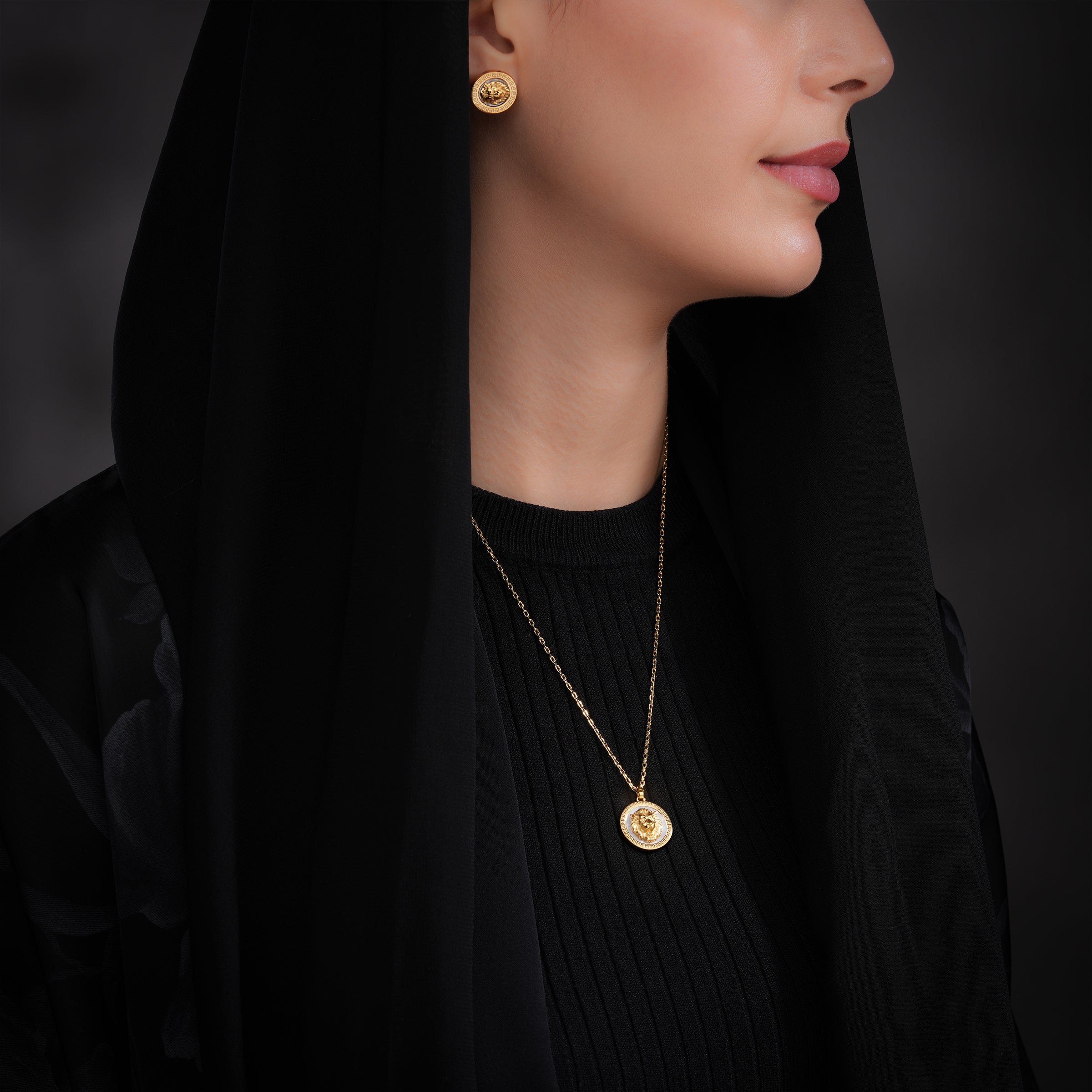 Gold-toned chain necklace with a round pendant featuring a white mother-of-pearl center, a gold-toned GL logo, and clear ston