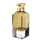 A three-quarter perspective view of the Galbee Paris Galbee Is Woody perfume bottle, showing its clear glass base, amber interior, and hexagonal gold cap.