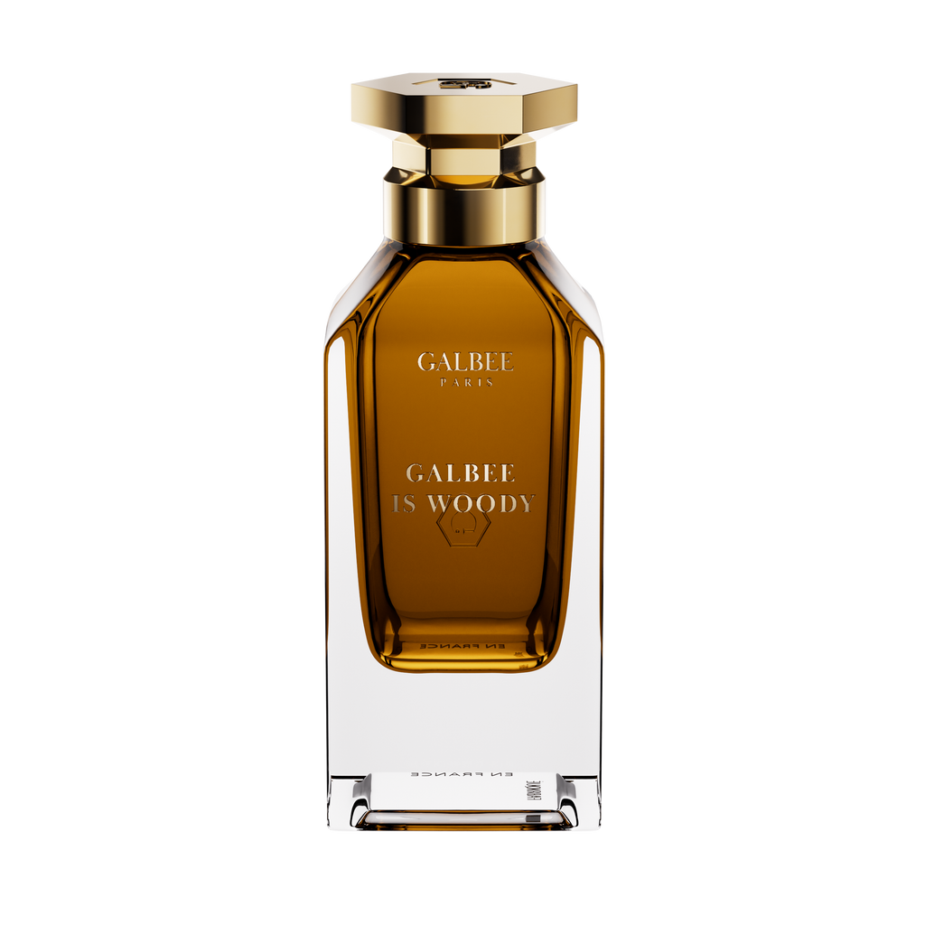A front-facing view of the Galbee Is Woody perfume bottle, highlighting the gold-etched branding and the signature hexagonal emblem on the glass.