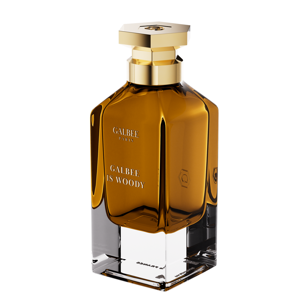 A three-quarter perspective view of the Galbee Paris Galbee Is Woody perfume bottle, showing its clear glass base, amber interior, and hexagonal gold cap.
