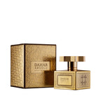 Gold-toned perfume bottle with a geometric cap and patterned sides, next to a matching embossed box. Both have "DAHAB ABSOLU"