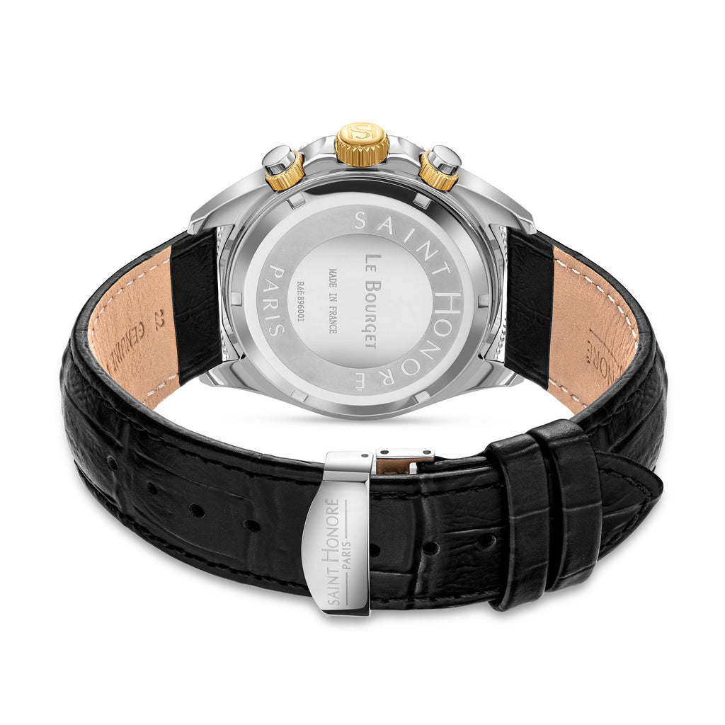 Back of a silver-toned watch with gold-toned crown, black crocodile-embossed leather strap with light brown interior, and sil