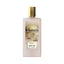 Frosted light pink rectangular perfume bottle with a gold-toned cap and an illustrated label depicting a golden cityscape wit