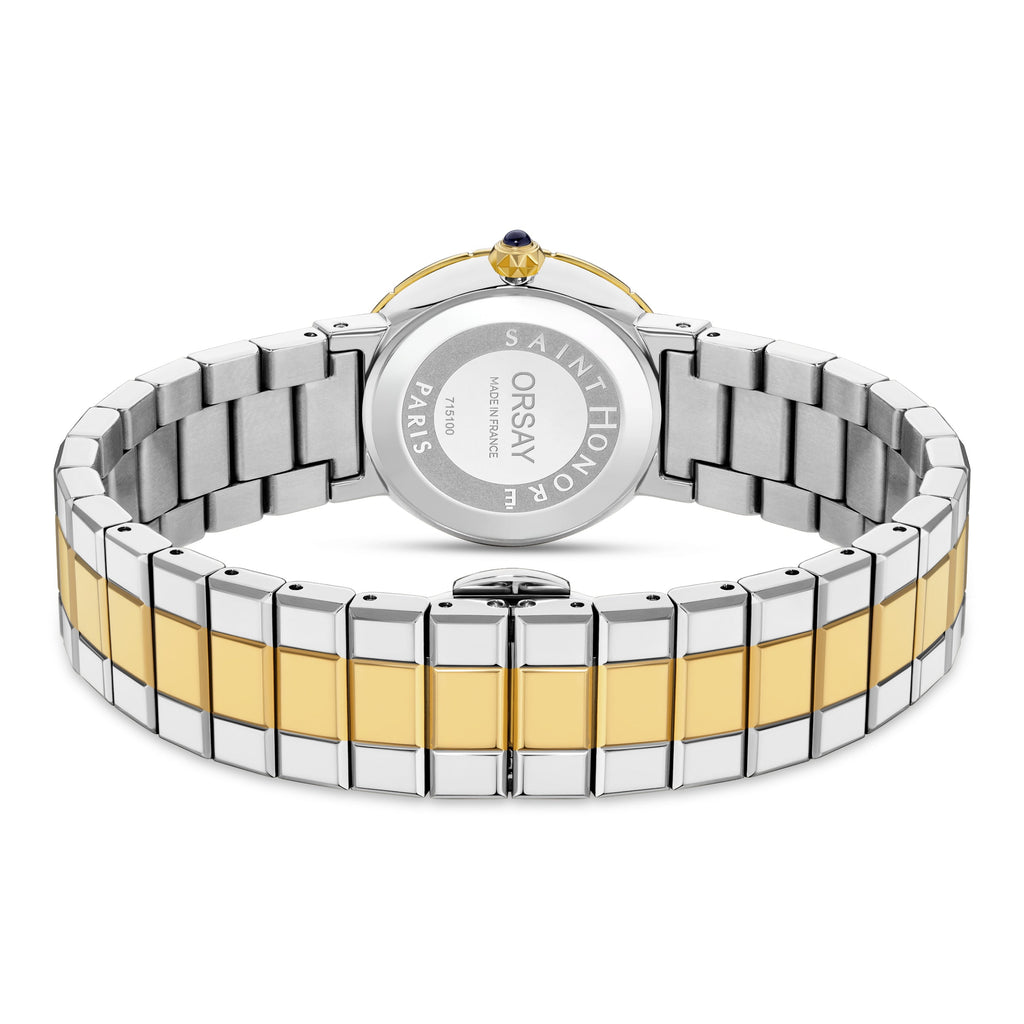 Back of a watch with a silver-toned case, gold-toned bezel, and crown with a dark blue stone. Two-toned silver and gold-toned