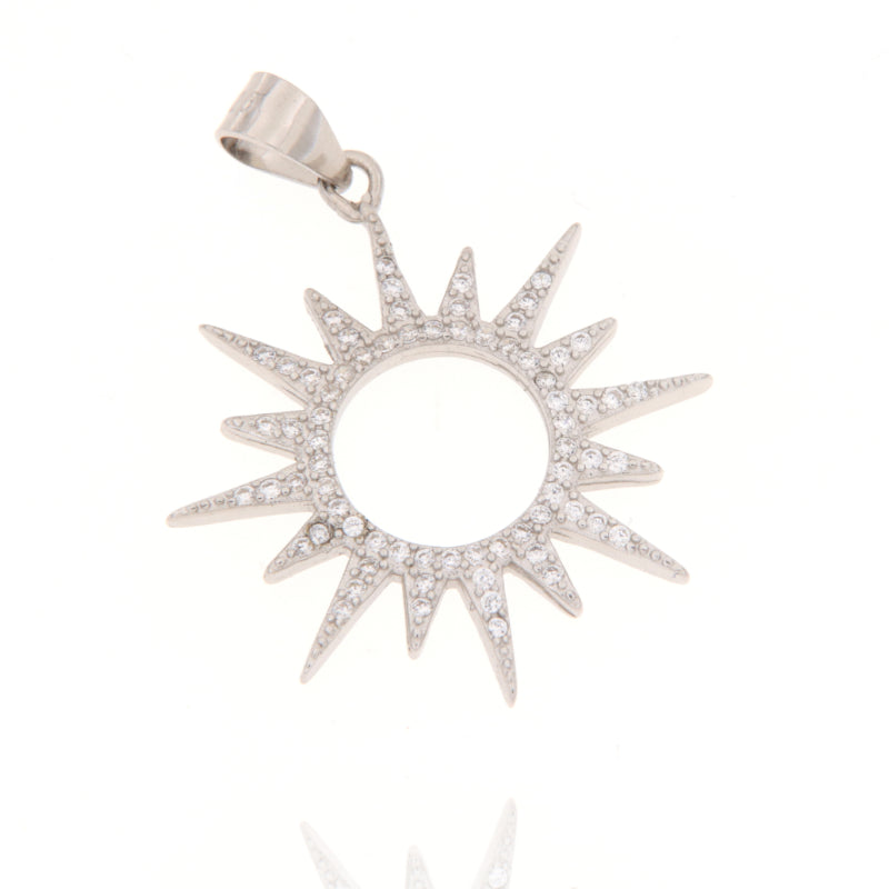 Silver-toned sunburst charm with a central circular cutout and pointed rays, pavé-set with clear cubic zirconia stones.