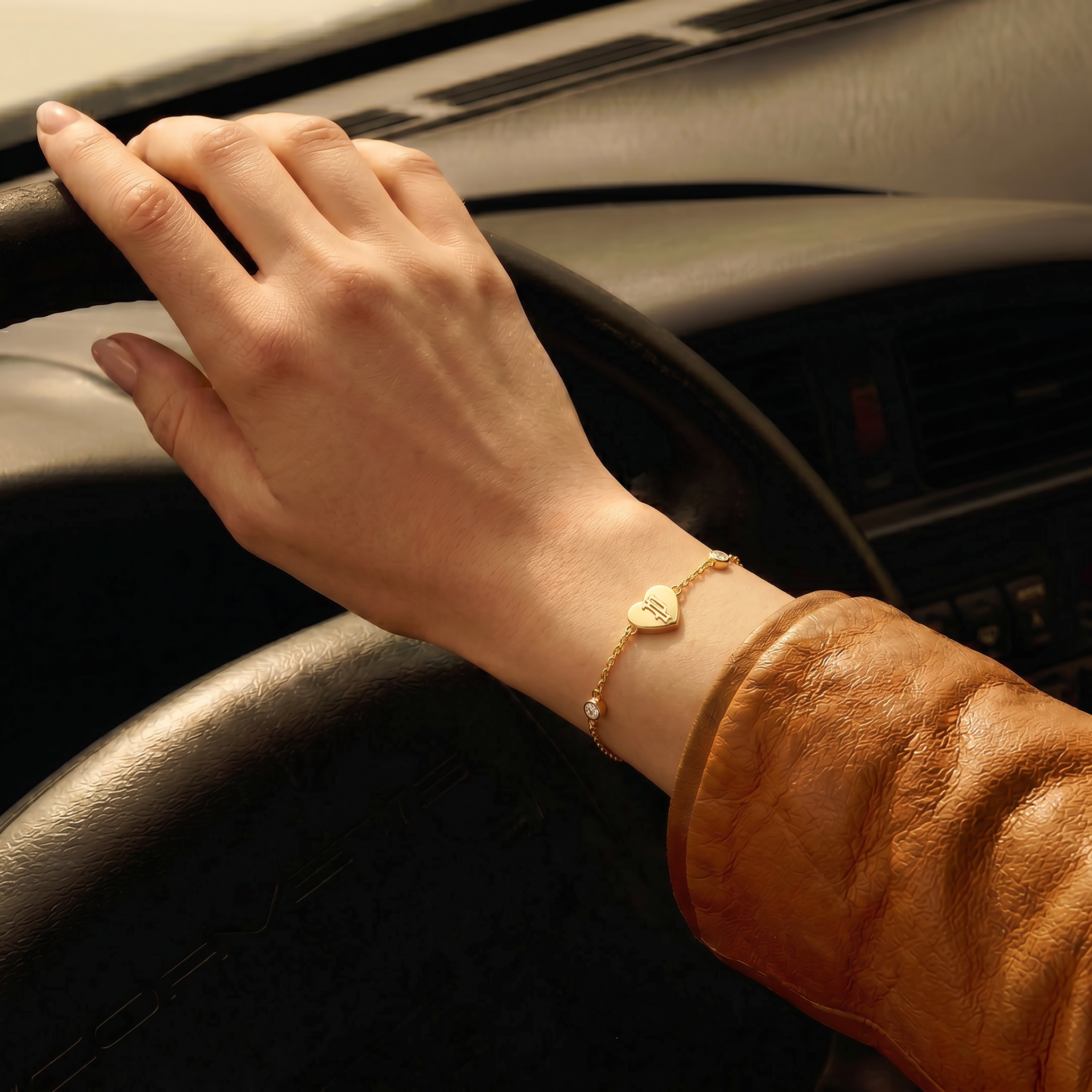 Gold-toned chain bracelet with a heart-shaped charm engraved with an 'M' and clear round crystals spaced along the chain.