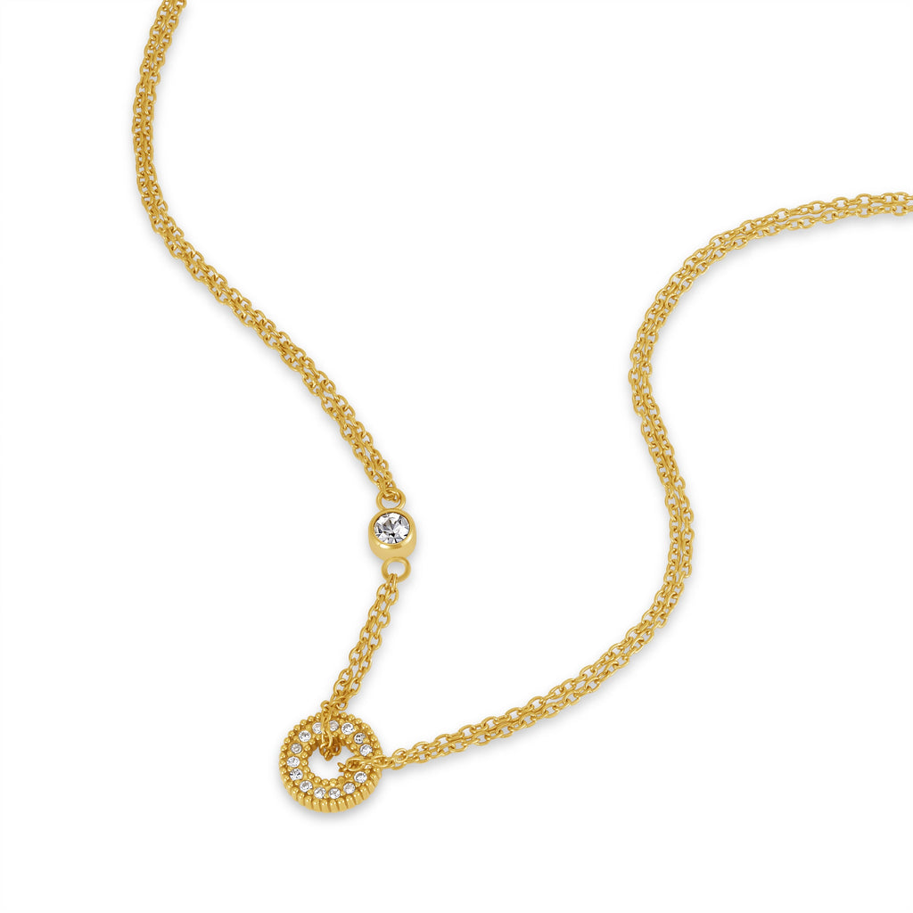 Gold-toned duochain necklace with a circular pendant featuring clear crystals forming the letter 'P', and a single clear crys
