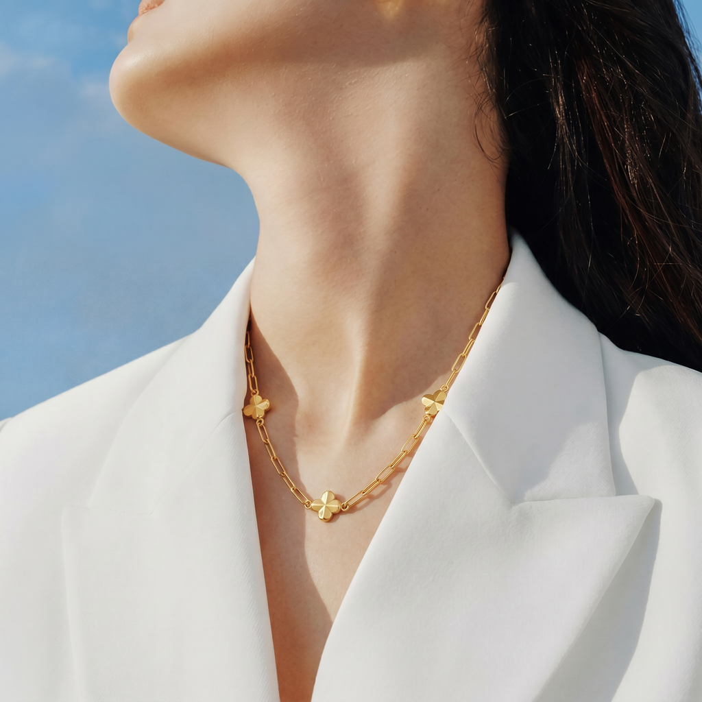 Gold-toned paperclip chain necklace with three matte gold-toned clover charms spaced along the chain.