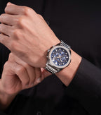 Silver-toned chronograph watch with a blue multi-dial face, silver-toned hour markers, and a metal link bracelet.